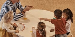 children play and learn at table with a teacher