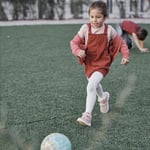 girl runs after a ball in a playground 