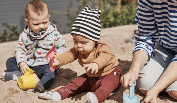 babies in sand  having sensory experiences with their teacher